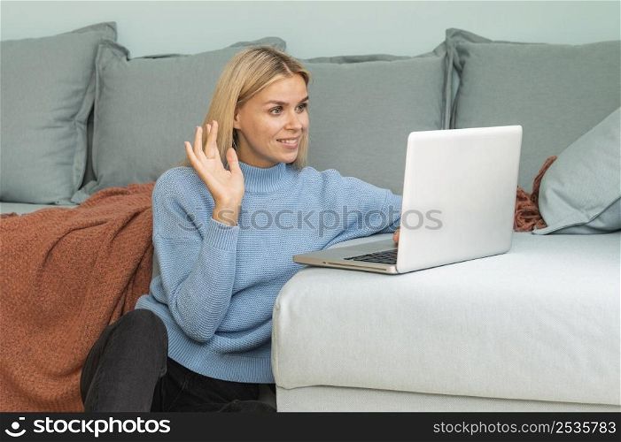 woman having video call home laptop waving during pandemic