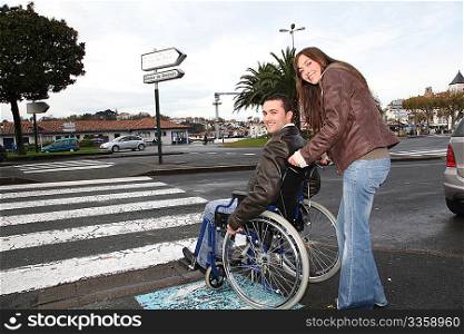 Woman helping friend in wheelchair cross the street