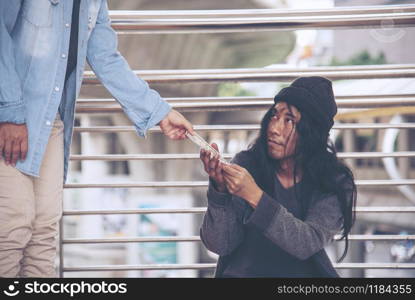 Woman helping hands to homeless people poverty beggar man holding hands asking for money job and hoping help in helpless dirty city sitting on streets. Desperate Beggar in city concept.