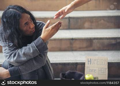 Woman helping hands to homeless people poverty beggar man holding hands asking for money job and hoping help in helpless dirty city sitting on streets. Desperate Beggar in city concept.