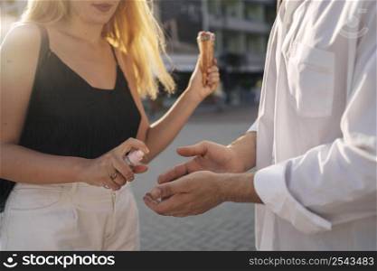 woman helping her boyfriend disinfect his hands