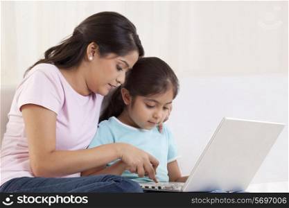 Woman helping her daughter to use a laptop