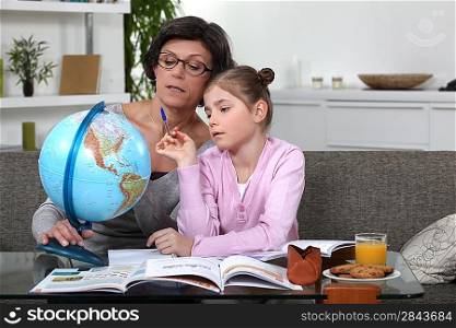 Woman helping her granddaughter complete her geography homework