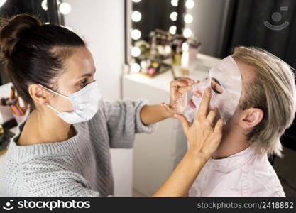 woman helping man applying facial mask