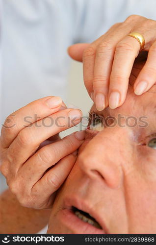 Woman helping man put in contact lenses