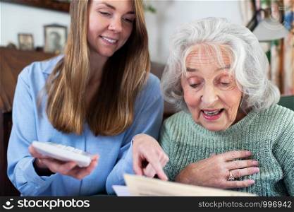 Woman Helping Senior Neighbor With Bills And Paperwork