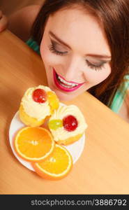 Woman hidden behind table sneaking and looking at delicious cake with sweet cream and fruits on top. Appetite and gluttony concept.. Woman looking at delicious sweet cake. Gluttony.