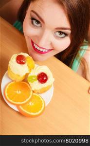 Woman hidden behind table sneaking and looking at delicious cake with sweet cream and fruits on top. Appetite and gluttony concept.. Woman looking at delicious sweet cake. Gluttony.