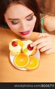 Woman hidden behind table sneaking eating and tasting delicious cake with sweet cream and fruits on top. Appetite and gluttony concept.. Woman eating delicious sweet cake. Gluttony.