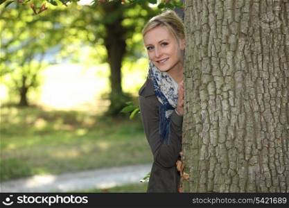 Woman hiding behind a tree