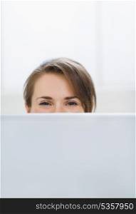 Woman hiding behind laptop