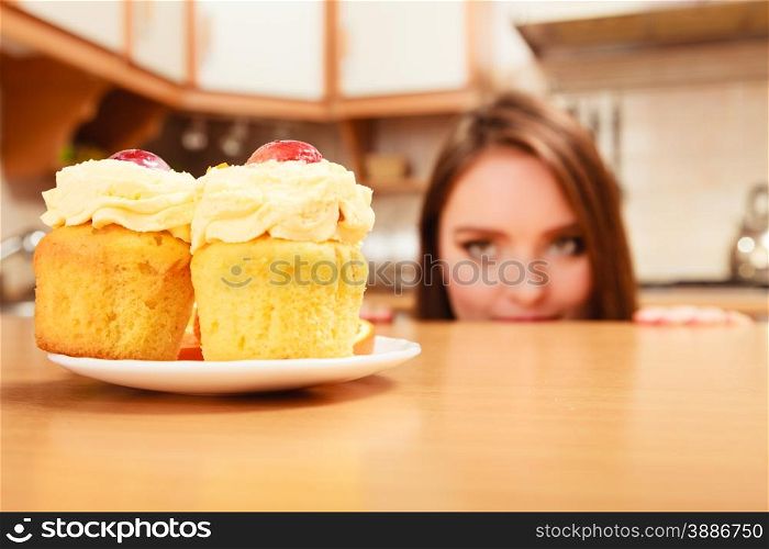 Woman hiding behind table sneaking and looking at delicious cake with sweet cream and fruits on top. Appetite and gluttony concept.. Woman looking at delicious sweet cake. Gluttony.
