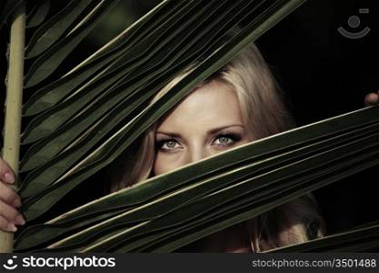 woman hiding behind the palm leaves
