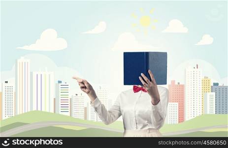 Woman hiding face behind book. Woman with opened book against her face pointing with finger