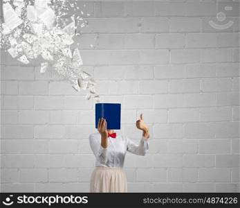 Woman hiding face behind book. Woman with opened book against her face showing thumb up