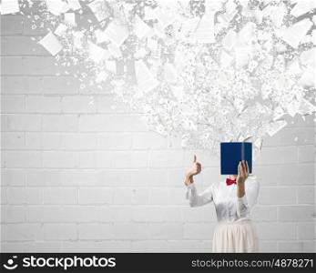 Woman hiding face behind book. Woman with opened book against her face showing thumb up
