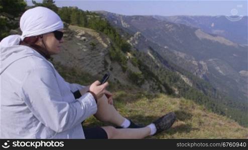 Woman hiker listening to music while enjoying the view from the mountain top of Ai-Petri Crimea