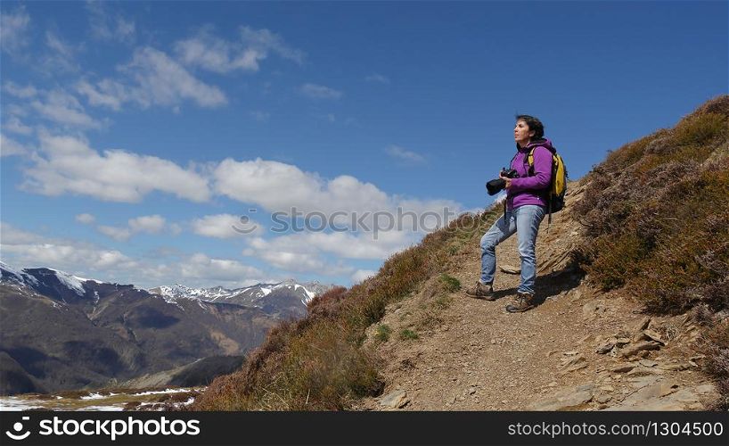 woman hiker with camera and backpack taking picture of beautiful mountain