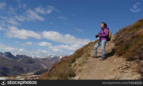 woman hiker with camera and backpack taking picture of beautiful mountain