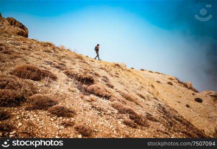 Woman hiking along beautiful mountains, active female with backpack traveling along high mountaing, enjoying vacation and freedom