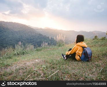 woman hiking with backpack relaxing in nature and enjoy the sunset view on mountain peak at Mae Wong national park Thailand.