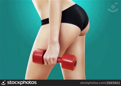 woman hips and red dumbbell in left hand on green background