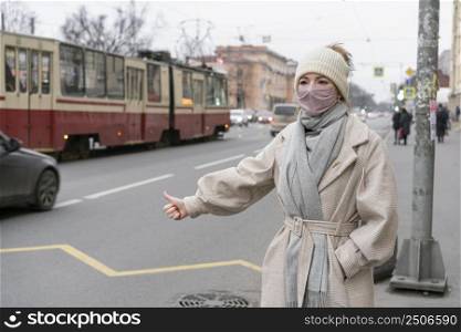 woman hitchhiking city while wearing mask