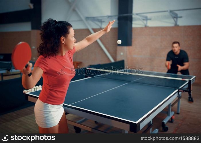 Woman hits the ball, table tennis, ping pong players. Couple playing table-tennis indoors, sport game with racket, active healthy lifestyle. Woman hits the ball, table tennis, ping pong