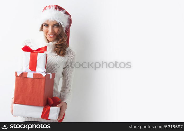 Woman hold Christmas gifts. Young woman in Santa hat holding her Christmas gifts