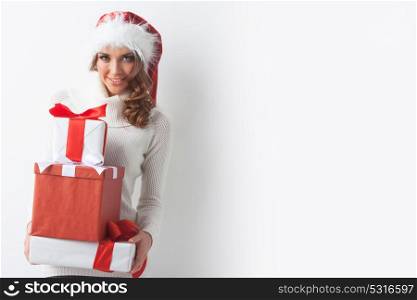 Woman hold Christmas gifts. Young woman in Santa hat holding her Christmas gifts