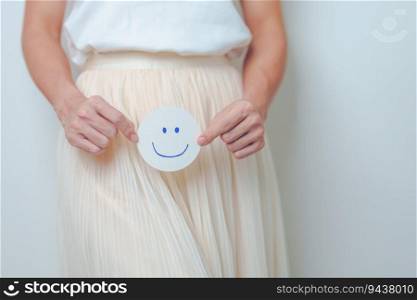 Woman hold Good and happy Face paper over abdomen. Ovarian and Cervical cancer, Endometriosis, Hysterectomy, Uterine, Reproductive, menstruation, Infertility, Pregnancy and Sexual Transmitted disease
