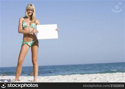 Woman holding a blank card on a beach
