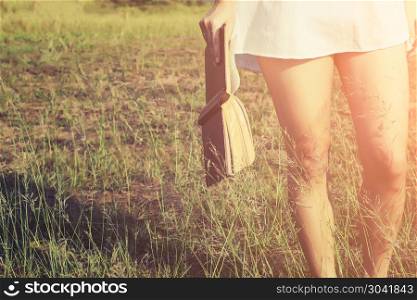 Woman holding a book in meadows on the sunshine of morning.
