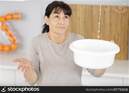 woman holding a bucket with leakage water falling