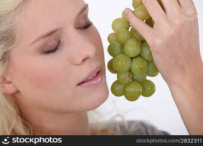 Woman holding a bunch of grapes next to her face