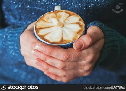 Woman holding a cup of coffee latte with beautiful pattern. The art of making cappuccino