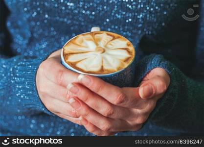 Woman holding a cup of coffee latte with beautiful pattern. The art of making cappuccino