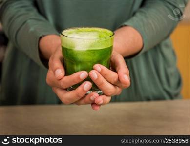 Woman holding a glass of green juice. Preparing a detox juice.