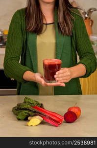 Woman holding a glass of red juice. Preparing a detox juice.