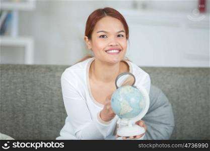 woman holding a globe and magnifying glass