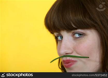 Woman holding a green bean between her lips and her nose