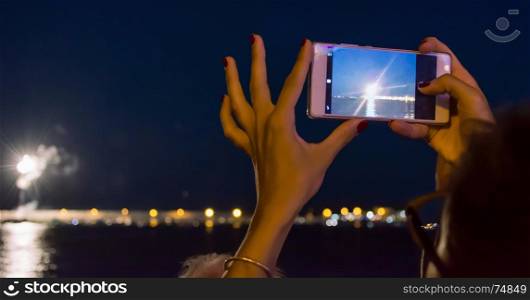 woman holding a mobile smart phone to take photo of firework