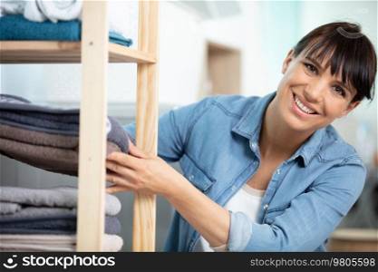 woman holding a pile of ironed clean towels standing