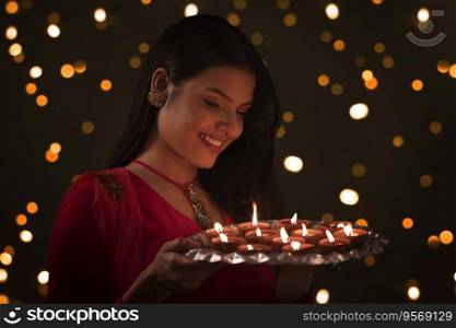 Woman holding a plate of diyas in hands and smiling