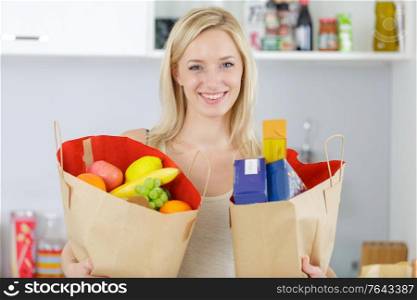 woman holding a shopping bags full of vegetables