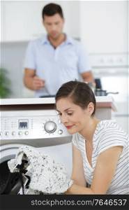 woman holding a shrunken shirt in front of washing machine