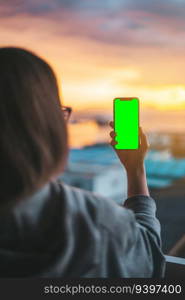 Woman holding a smartphone on a green screen