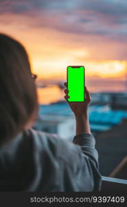 Woman holding a smartphone on a green screen