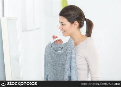 woman holding a top in front of the mirror