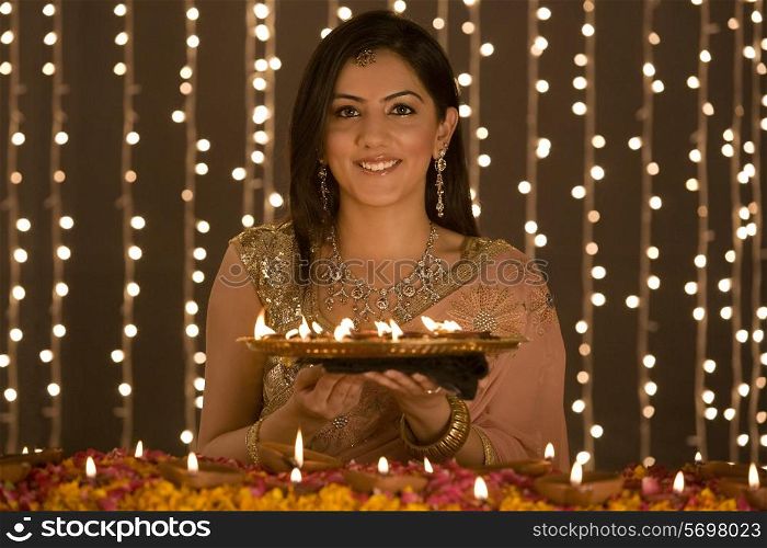 Woman holding a tray of diyas